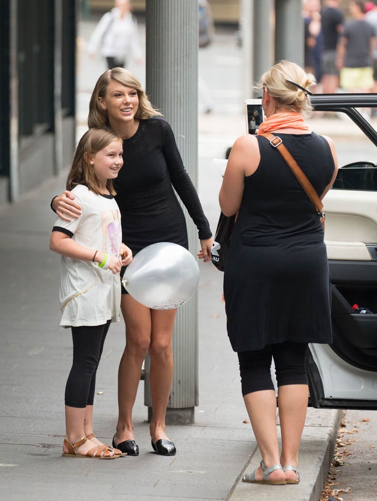Taylor Swift stops in the middle of a busy road in Sydney to take a photo with a little girl who was wearing a Taylor Swift t-shirt