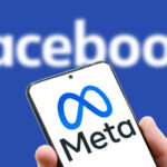 Meta logo on screen of mobile phone on Facebook word background
